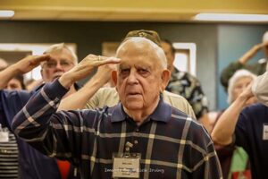 Veterans salute during National Anthem at Roll Call Luncheon December 2022